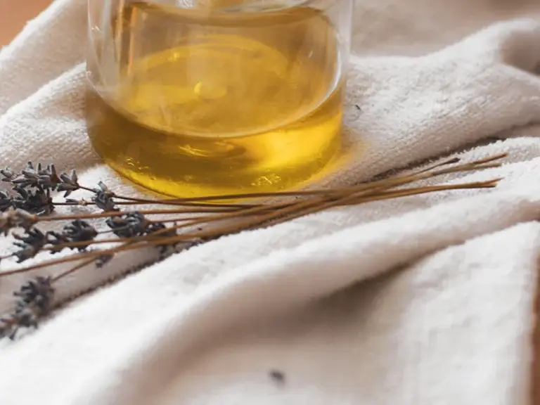 Massage oil jar with lavender on white towel – ingredients for massage and body oils